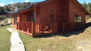 Una cabaña de madera con un porche, una puerta y una ventana.