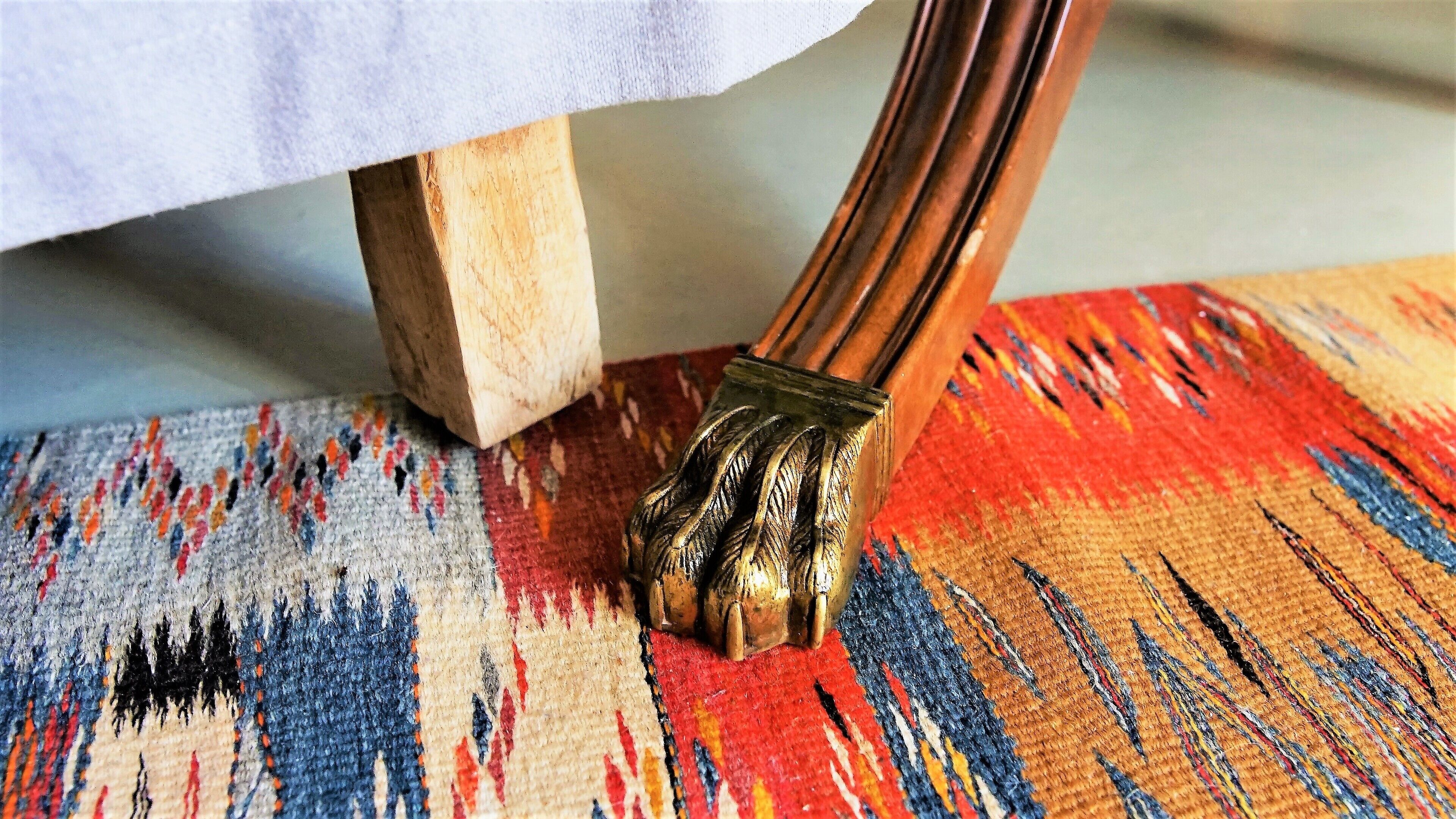 Un gros plan d’un pinceau à manche en bois, posé sur un tapis coloré à motifs tissés.
