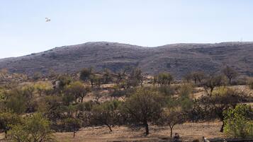 A dry, hilly landscape with sparse vegetation and a clear sky.