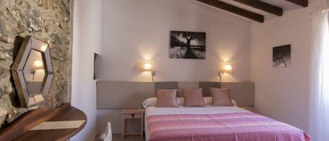 A bedroom with a bed, two bedside tables, a nightstand, a wall-mounted mirror, and a painting.