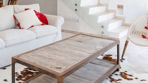 A modern living room with a white staircase, a white sofa, a wooden coffee table, and a cowhide rug. - Casa Das Cegonhas (Alcacer do Sal)