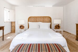 A large bed with a wooden headboard, white bedding, and two bedside lamps.