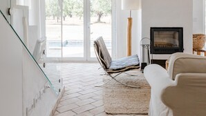 A spacious living area with a fireplace, a mounted deer head, and a large window offering a view of the outdoors. - Casa Das Cegonhas (Alcacer do Sal)