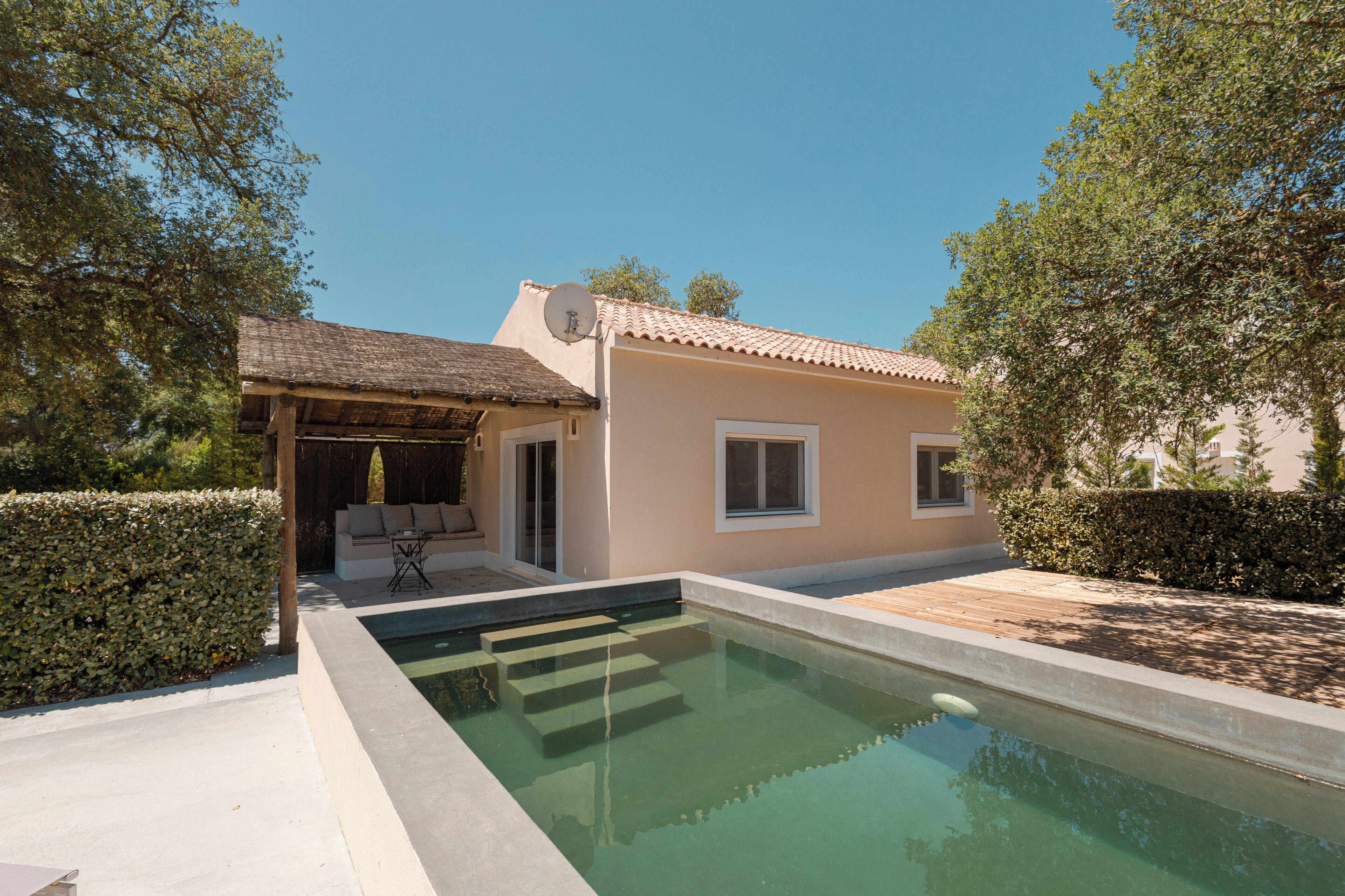 Une maison moderne dotée d’une piscine, d’un patio et d’un espace extérieur aménagé et couvert.