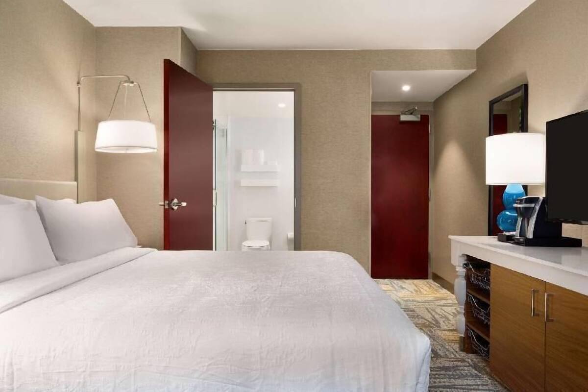 Een hotelkamer met een bed, een televisie, een bureau met lamp en een kledingkast.