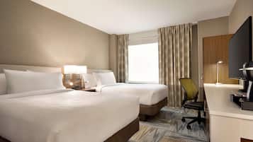 Une chambre d’hôtel avec deux lits, un bureau, une chaise, une télévision et une fenêtre avec des rideaux.