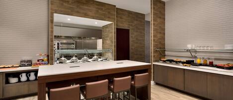 Una cocina moderna con una isla central, taburetes de bar y una barra desayunadora.