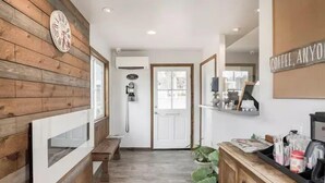 A hallway with wooden paneling, a clock, a coffee machine, and a sign that says "Coffee, Anyone?". - Ramona Valley Inn (Ramona)