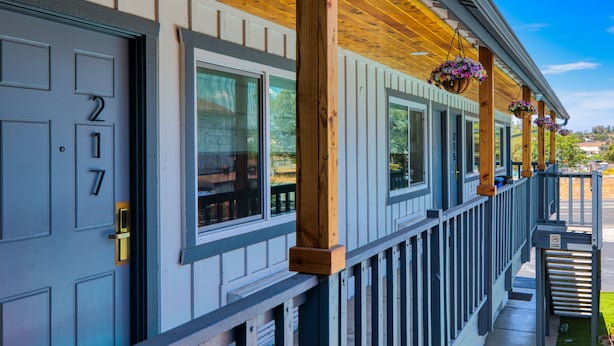 A building with a porch, wooden beams, and hanging flower baskets. - Ramona Valley Inn (Ramona)