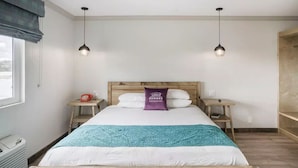 A bedroom with a wooden bed, two bedside tables, a window with blinds, and two pendant lights. - Ramona Valley Inn (Ramona)