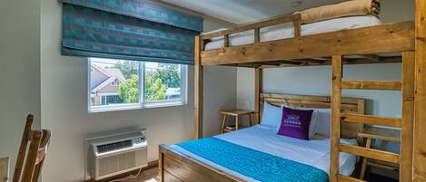 Une chambre avec un lit superposé, une fenêtre, un radiateur et une chaise.