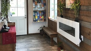 A hotel lobby with a wooden wall, a bulletin board with travel brochures, a bench, and potted plants. - Ramona Valley Inn (Ramona)