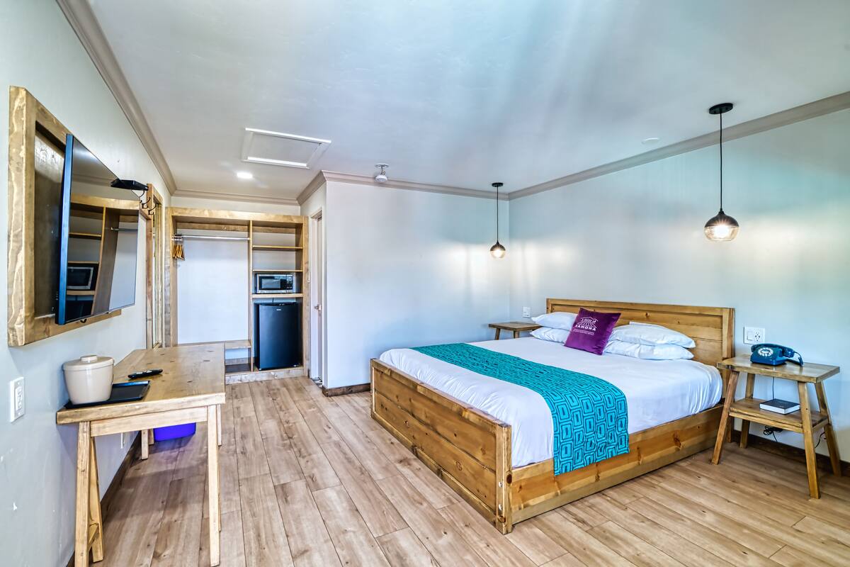 Una camera da letto con un letto di legno, una scrivania, un tavolino e uno specchio.