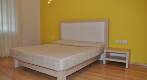 Un dormitorio con cama, mesita de noche y enchufe.