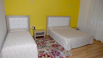 Una stanza con due letti singoli, un comodino e un tappeto colorato.
