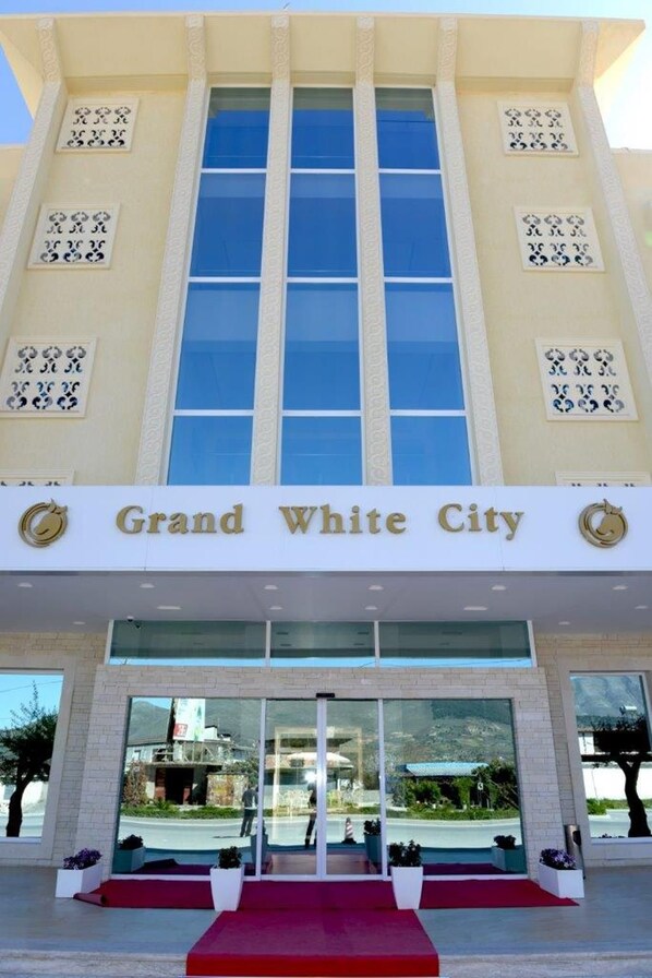 A hotel entrance with a sign reading 'Grand White City.'