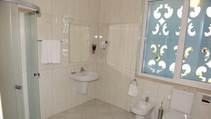 A bathroom with a glass shower enclosure, a sink, a bidet, and a toilet. - Grand White City (Velabisht)