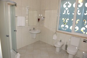 Un baño con cabina de ducha de vidrio, lavamanos, un bidé y un inodoro.
