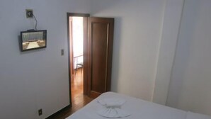 A bedroom with two beds, a wooden floor, a door leading to a hallway, and a wall-mounted TV. - Hotel Jau (Jau)