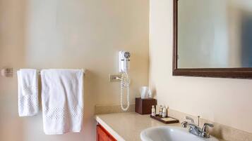 Un baño con un lavabo blanco, un espejo y dos toallas blancas colgadas en la pared.