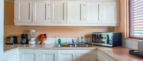 Una cocina con armarios blancos, microondas, tostadora y estufa.