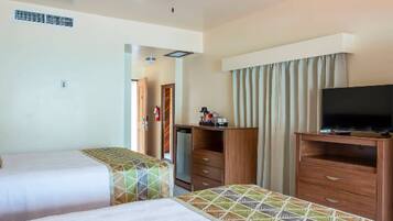 Habitació d'hotel amb dos llits, un ventilador de sostre, televisió i un armari.