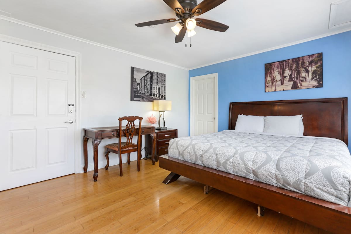A bedroom with a wooden bed, a desk with a chair, and a ceiling fan.