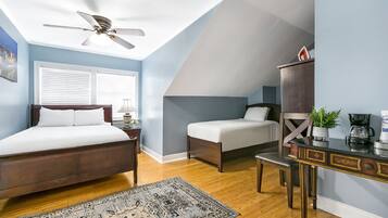 A bedroom with a bed, bedside table, lamp, and a desk with a chair.