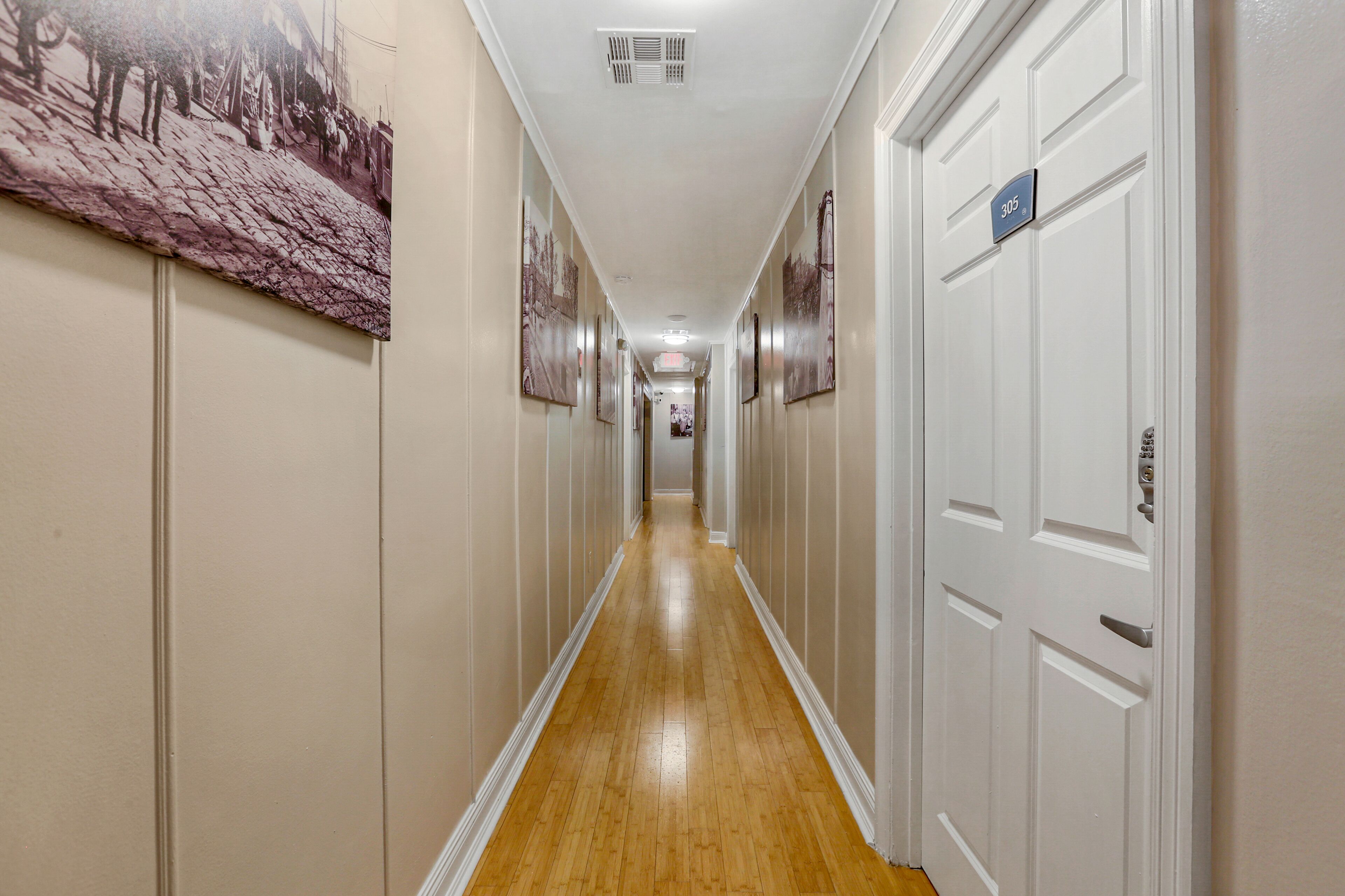 A hallway with wooden flooring, white walls, and doors on the right.