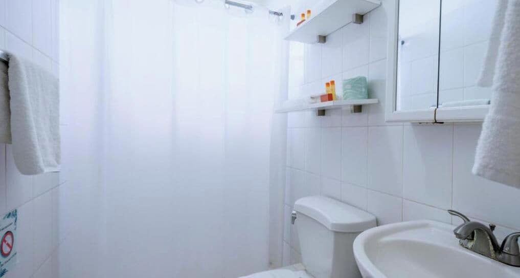 A bathroom with a toilet, sink, and shower area.