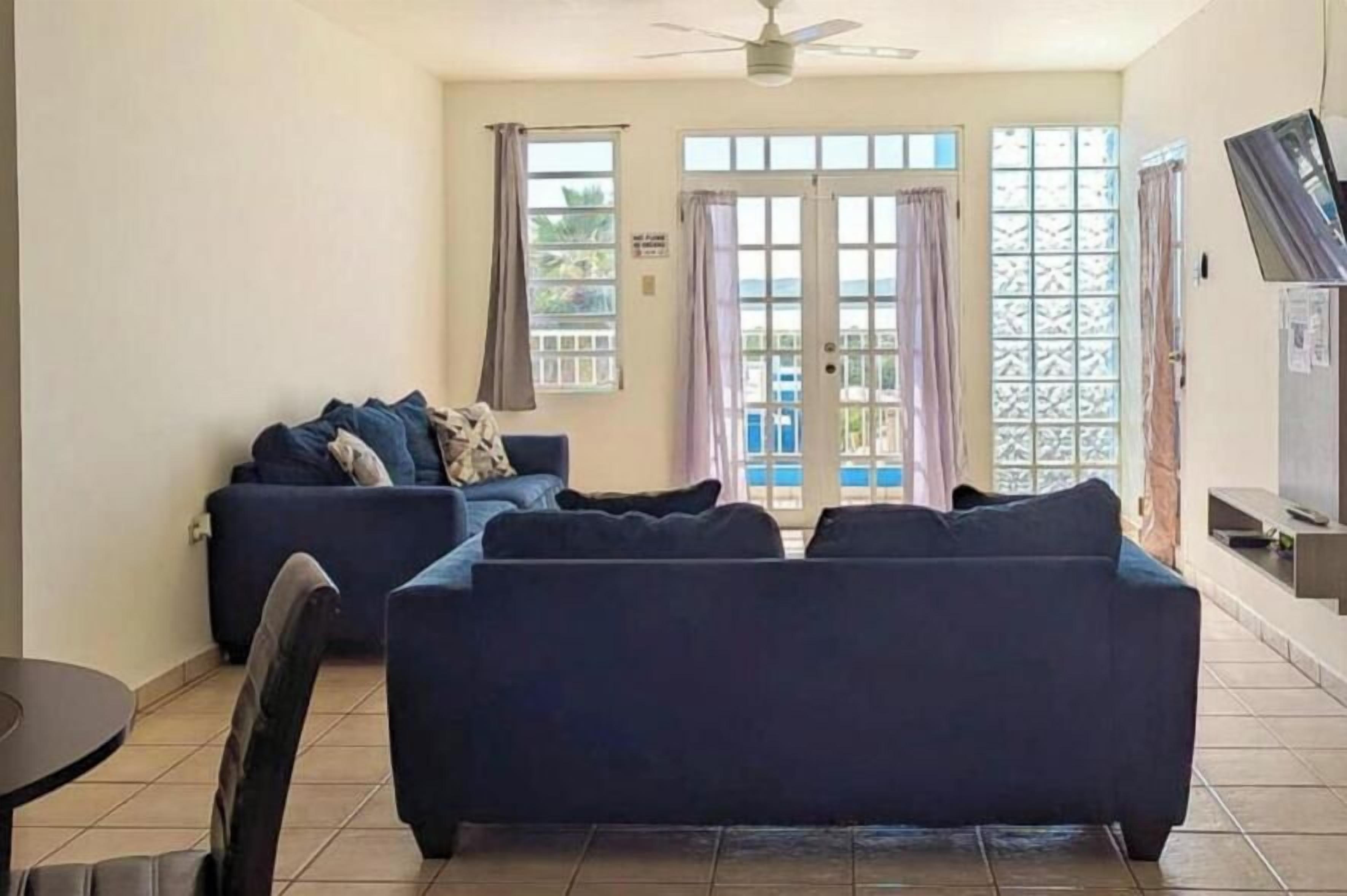 A living room with a sofa set, a television, and a view through a glass door.