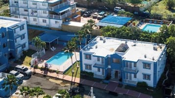 A multi-story hotel with balconies, a swimming pool, and a parking area.