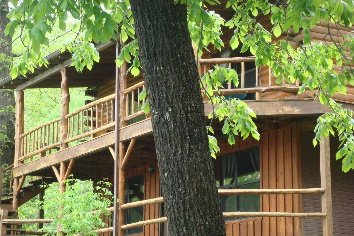Una cabaña de madera de varios pisos con un balcón en el nivel superior.