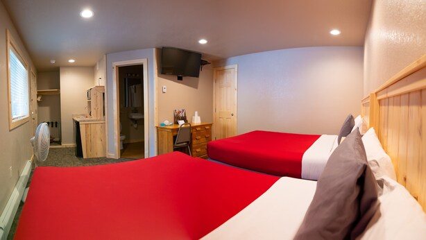 A hotel room with two beds, a desk, a chair, a TV, and a bathroom. - Triangle Motel (Silverton)