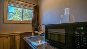 A kitchen with a window, a microwave, a coffee maker, and a sink. - Triangle Motel (Silverton)