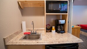 A compact kitchen with a stainless steel sink, a microwave, a coffee maker, and a small countertop. - Triangle Motel (Silverton)