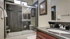 Une salle de bain moderne avec une douche à parois de verre, des toilettes blanches, un lavabo avec un meuble-vasque et un miroir.