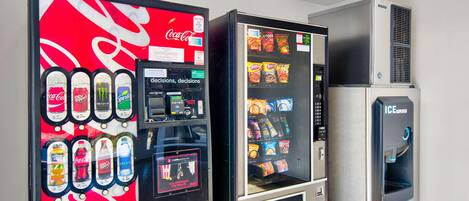 Una macchina distributrice con il logo Coca-Cola, un erogatore di bevande e una selezione di snack.