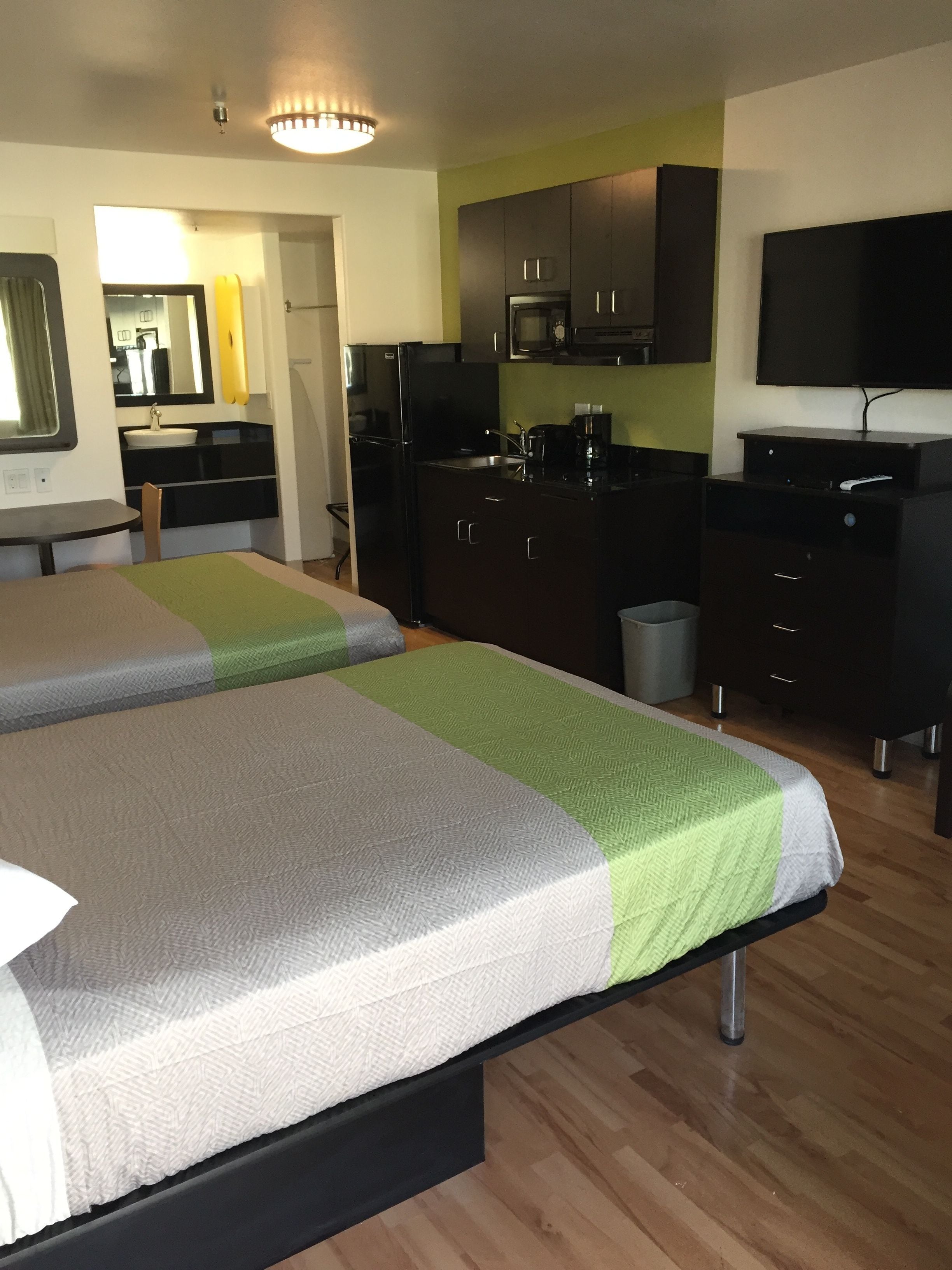 Une chambre d’hôtel avec deux lits, une kitchenette, une télévision et une salle de bain.
