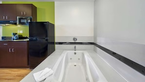 A modern kitchen with a built-in microwave, refrigerator, and a large white bathtub. - Studio 6 Victorville - Apple Valley (Victorville)