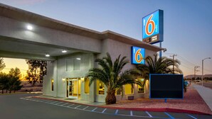 A motel with a prominent '6' sign, a parking lot, and palm trees. - Studio 6 Victorville - Apple Valley (Victorville)