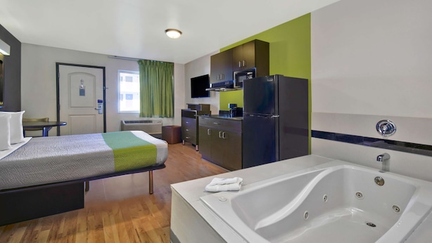 A hotel room with a bed, a bathroom with a bathtub, a kitchenette, and a TV. - Studio 6 Victorville - Apple Valley (Victorville)