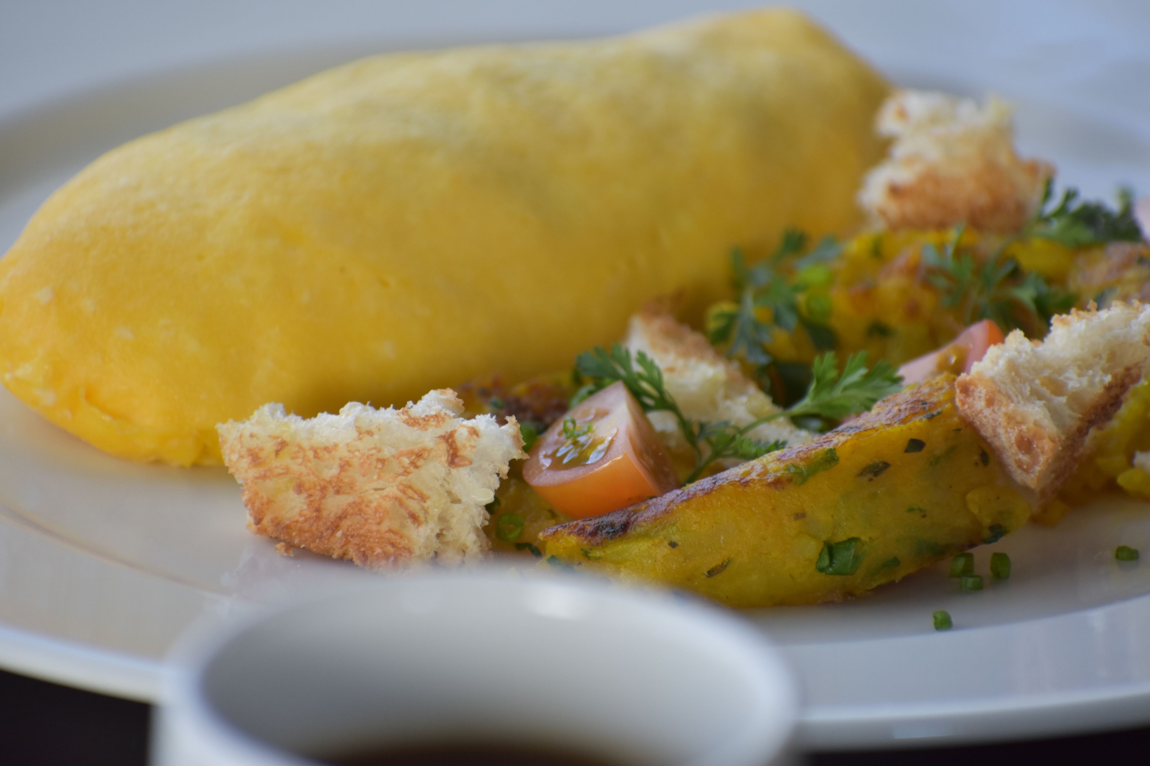 Un plato con tortilla amarilla, papas a la francesa y adorno de perejil.