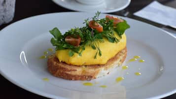 Un plato con comida para el desayuno, incluyendo tostadas, huevos revueltos y verduras frescas.