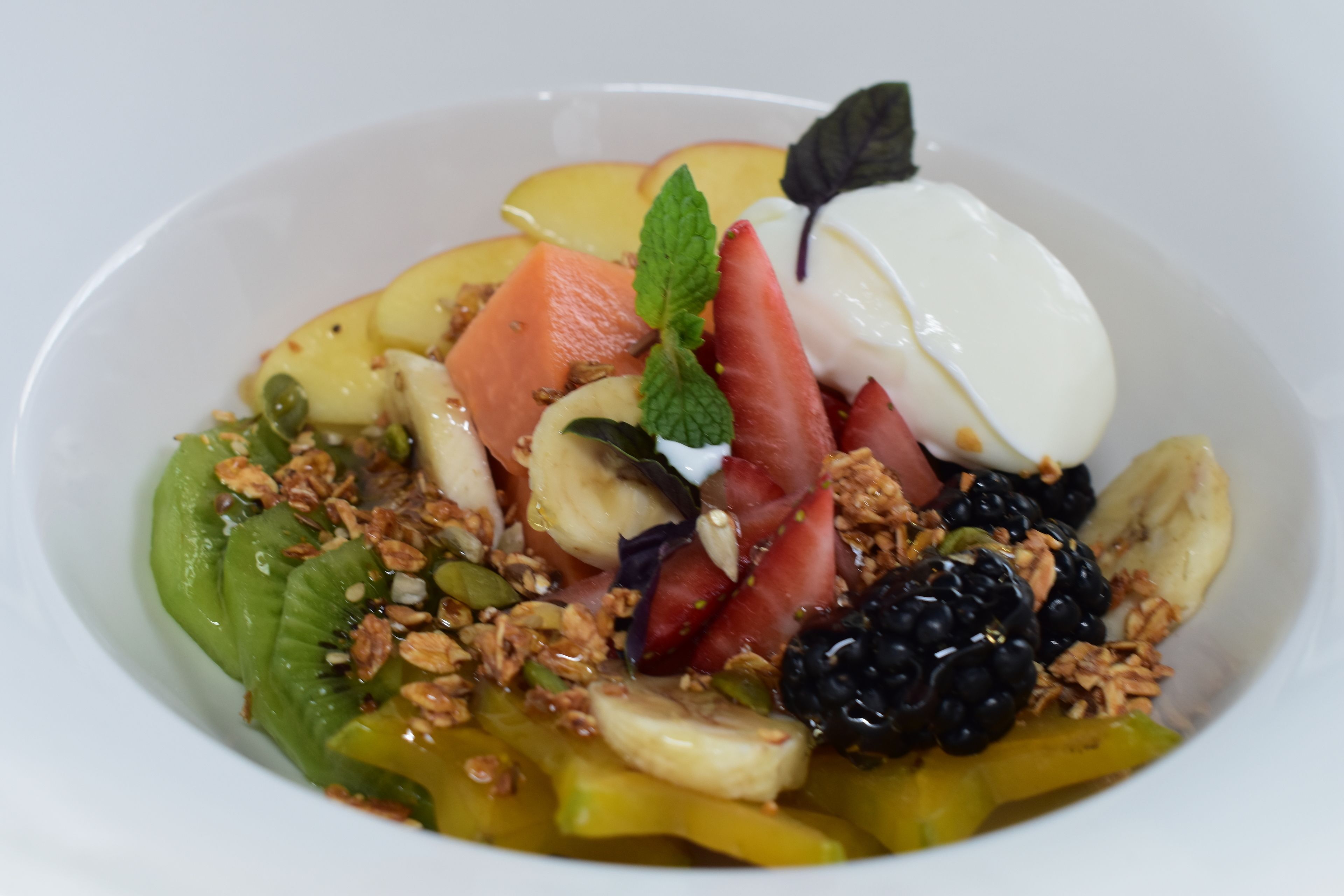 A bowl of fruit salad with various fruits and granola.