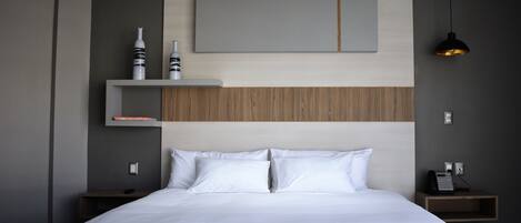 A modern bedroom with a large bed, a wooden headboard, and built-in shelves with decorative items.