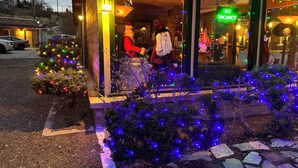 A storefront with a Christmas tree and a Santa Claus figure outside.