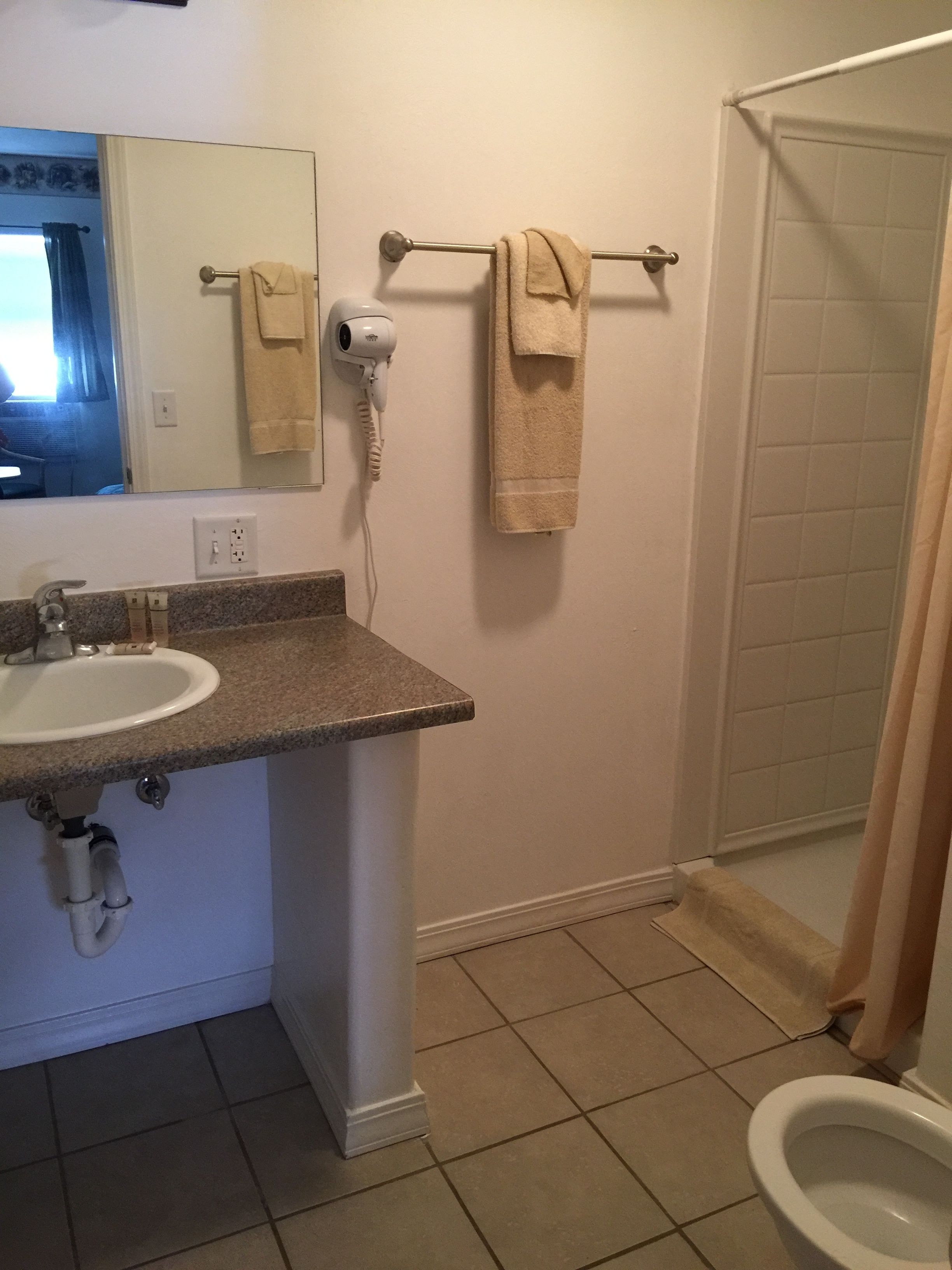 A bathroom with a sink, a hairdryer, and a towel rack.