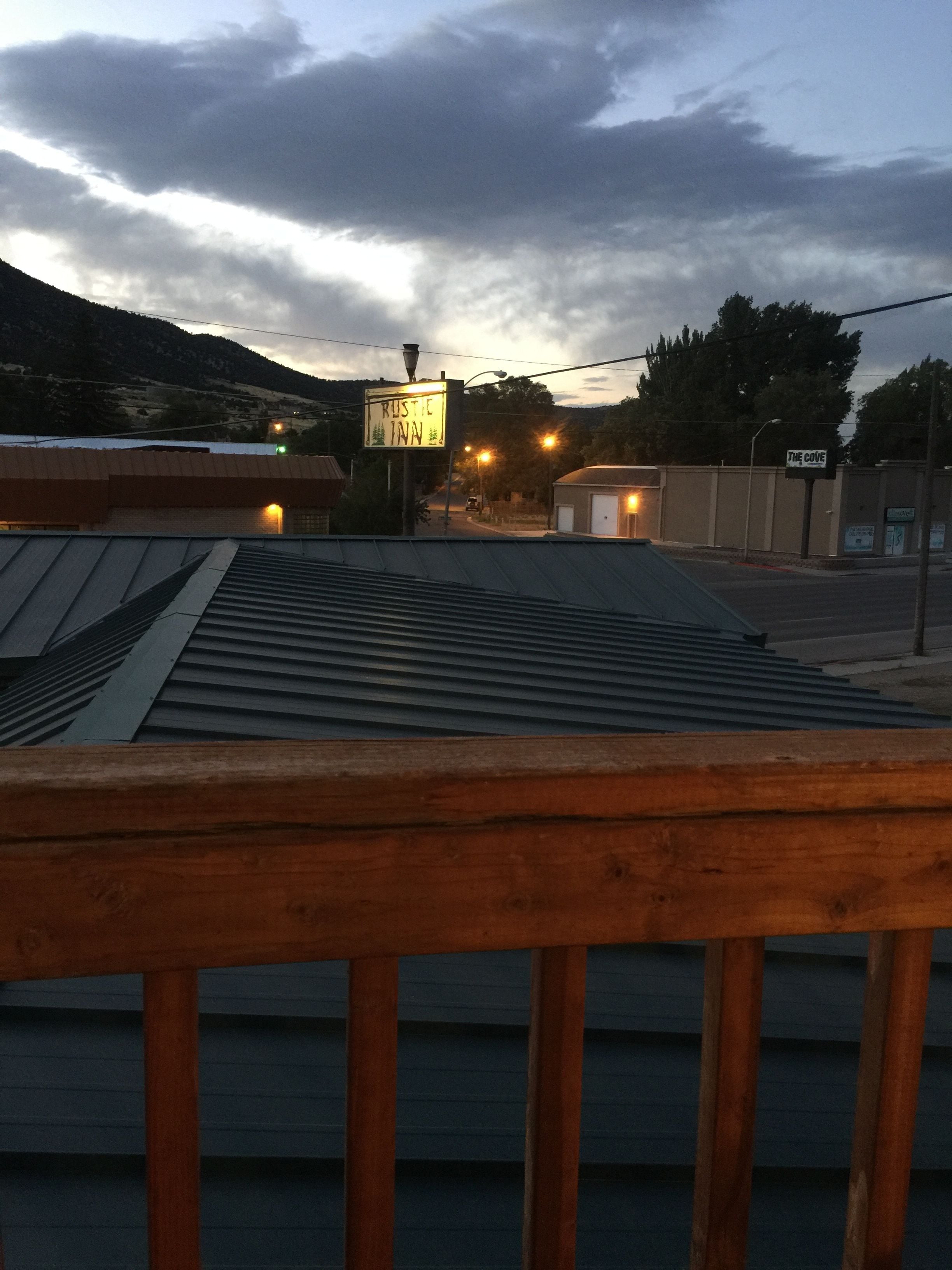 A view of a building with a metal roof and a wooden railing in the foreground. There are street lights and a sign that reads "Rustic Town."