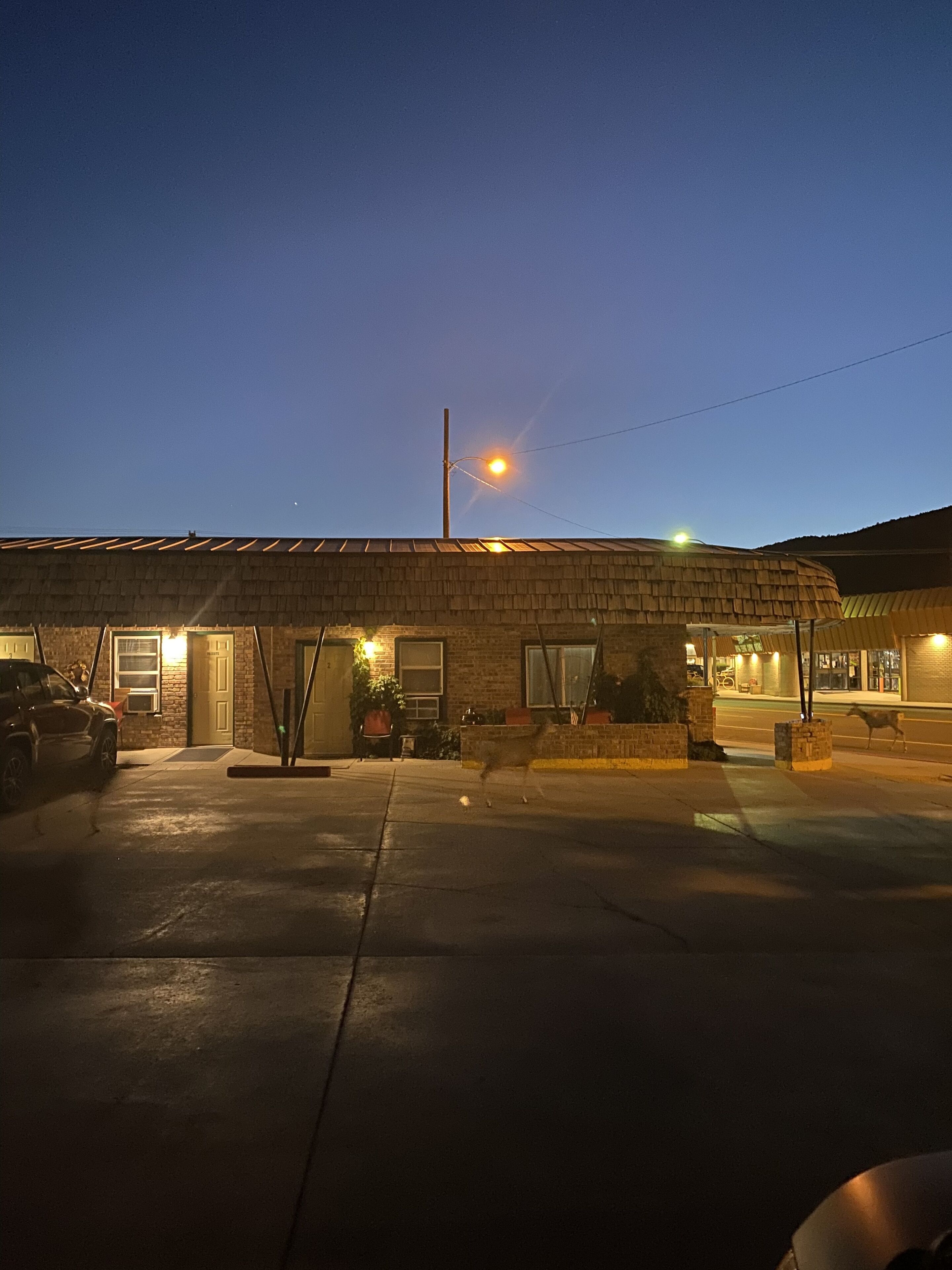 Un edificio con techo plano, entrada visible y zona de estacionamiento pavimentada.